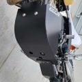 Black B&B aluminium bash plate fitted beneath an off-road motorcycle engine